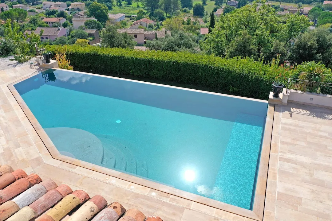 Piscine à débordement avec plage immergée en carrelage